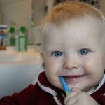 un bébé qui se brosse les dents avec une brosse en bambou