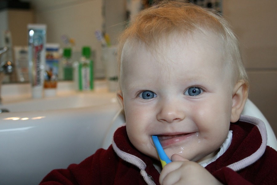 un bébé qui se brosse les dents avec une brosse en bambou