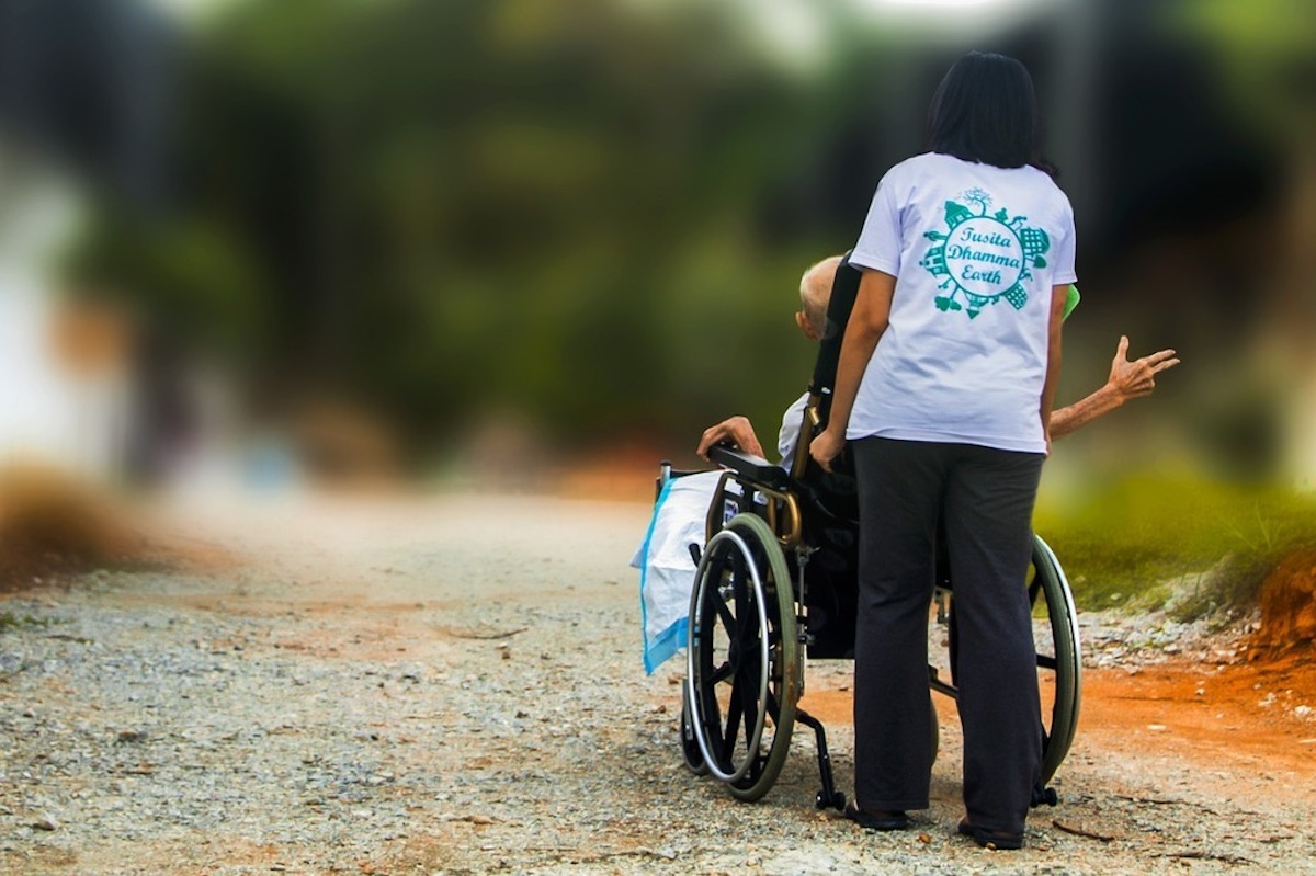 Handicapé moteur en fauteuil poussé par une bénévole